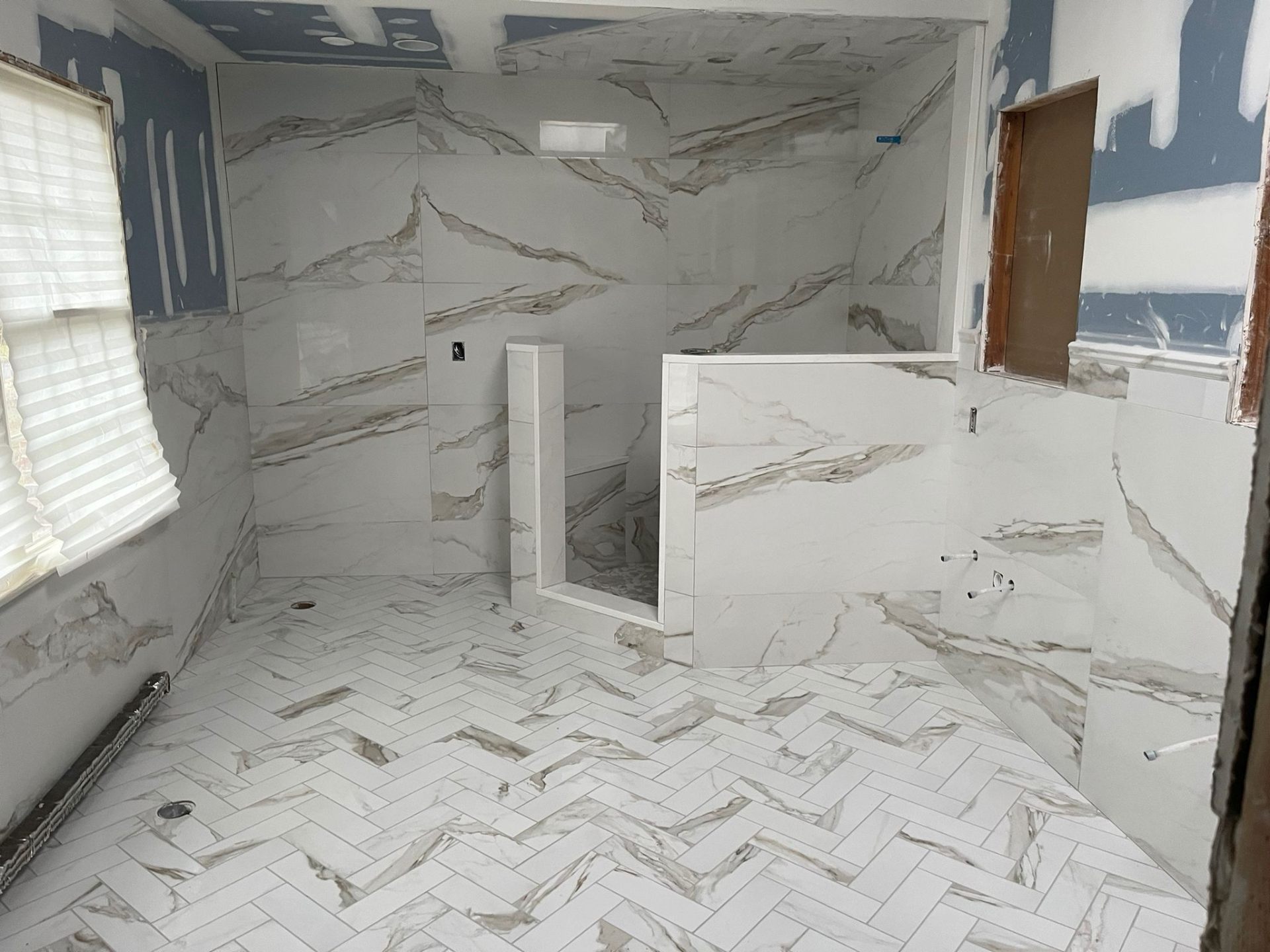Calacatta marble-look tile bathroom with herringbone floor